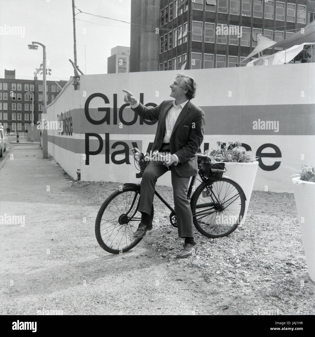 Actor and director Sam Wanamaker on his bicycle outside his proposed site for the Globe Playhouse theatre in London in 1972. The Sam Wanamaker Playhouse is an indoor theatre forming part of Shakespeare's Globe, along with the Globe Theatre on Bankside, London. Built making use of 17th-century plans for an indoor theatre, the playhouse recalls the layout and style of the Blackfriars Theatre, although it is not an exact reconstruction. Its shell was built during the construction of the Shakespeare's Globe complex, notable for the reconstruction of the open-air Globe Theatre of the same period. Stock Photo
