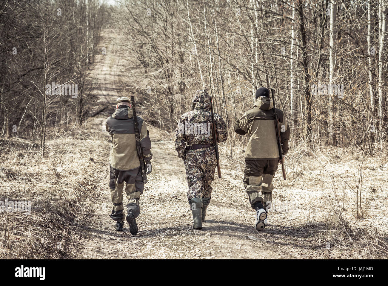 Group of men hunters outgoing on rural road during hunting season Stock Photo