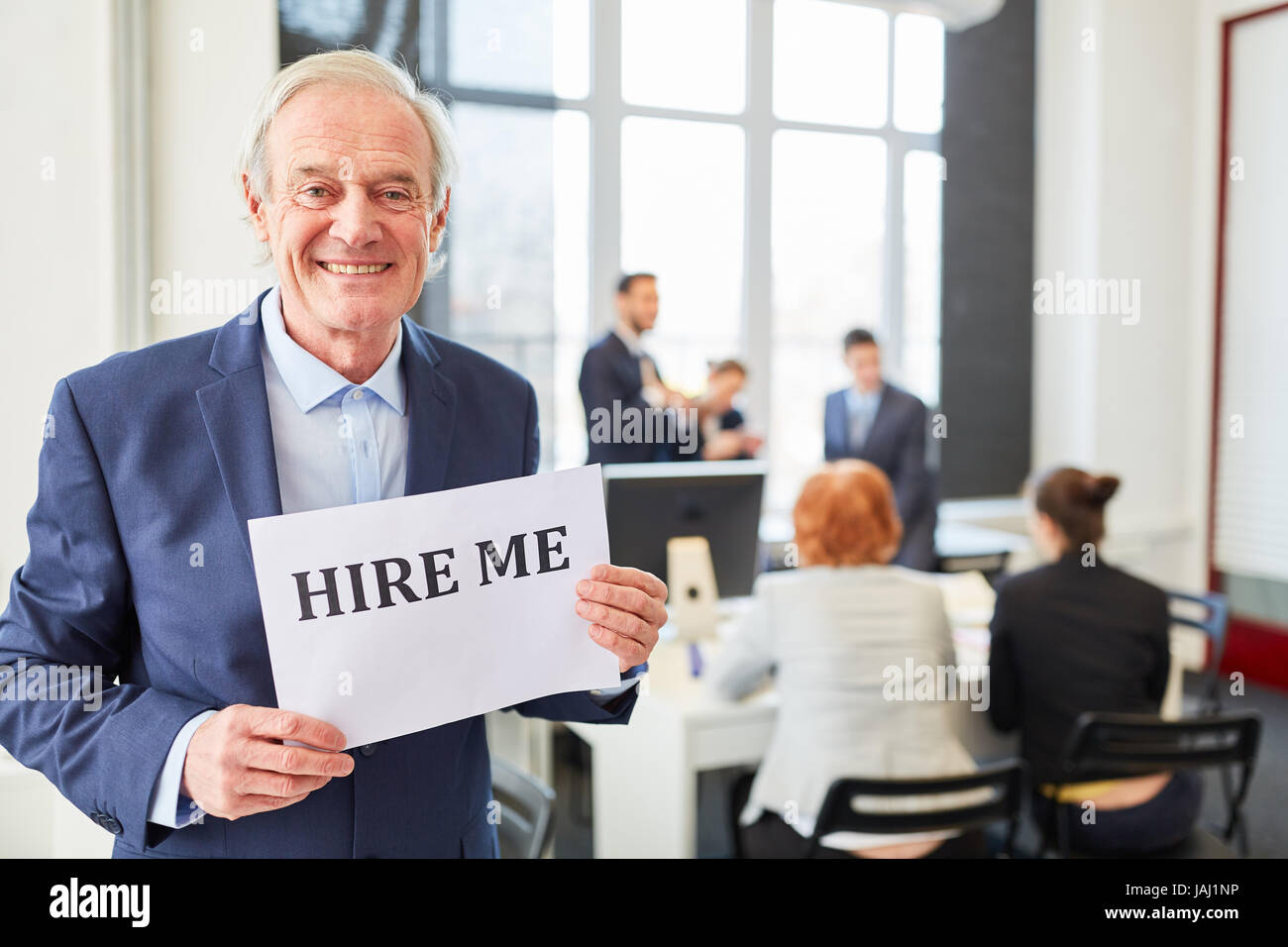 Senior businessman looking for a job holds sign that reads 'hire me' Stock Photo
