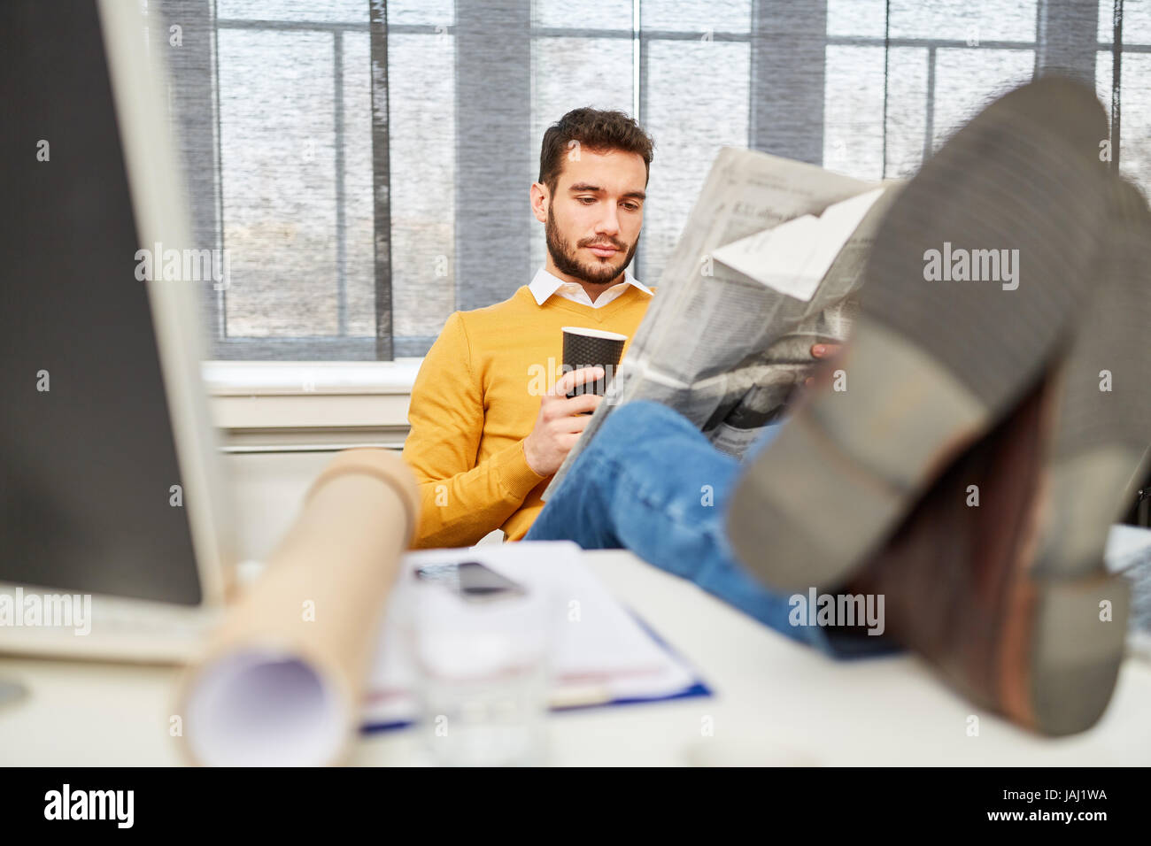 Man reading newspaper at office during coffee break relaxation Stock Photo