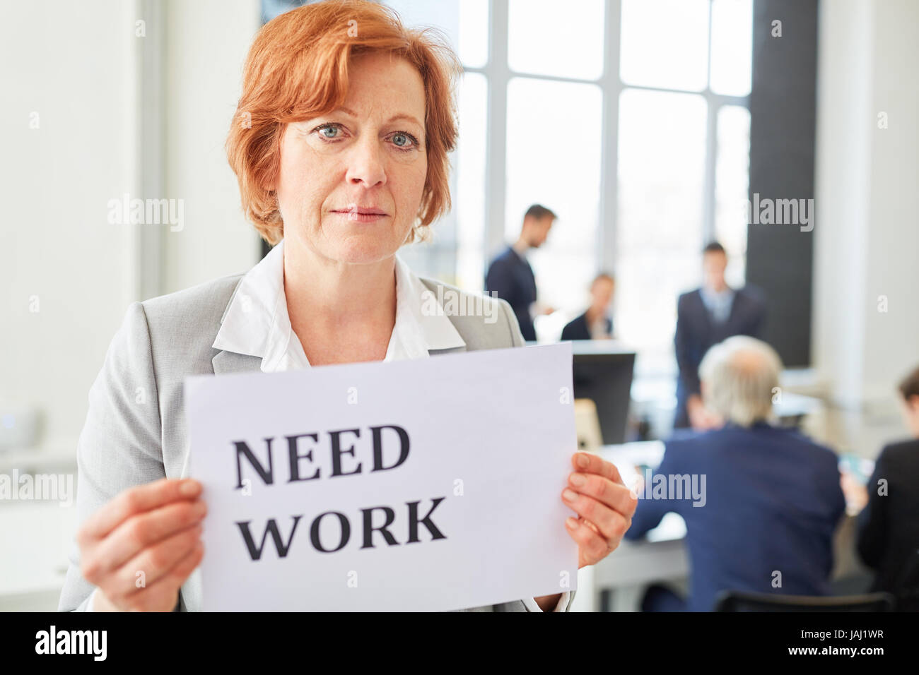 Senior businesswoman as candidate holding sign that reads 'need work' Stock Photo