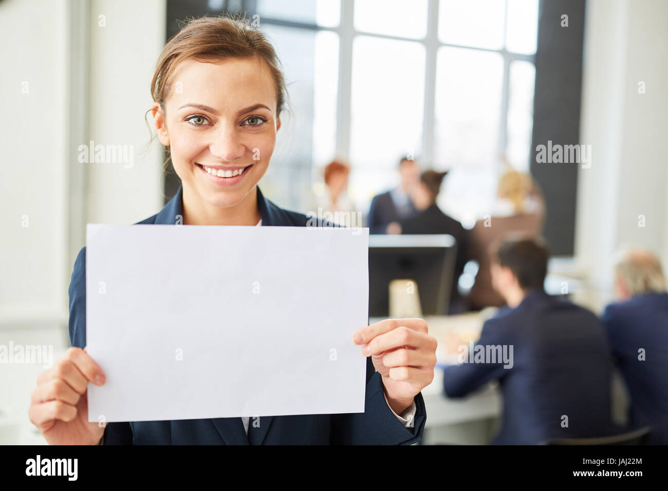 Happy woman smiling holds blank sign in business office Stock Photo