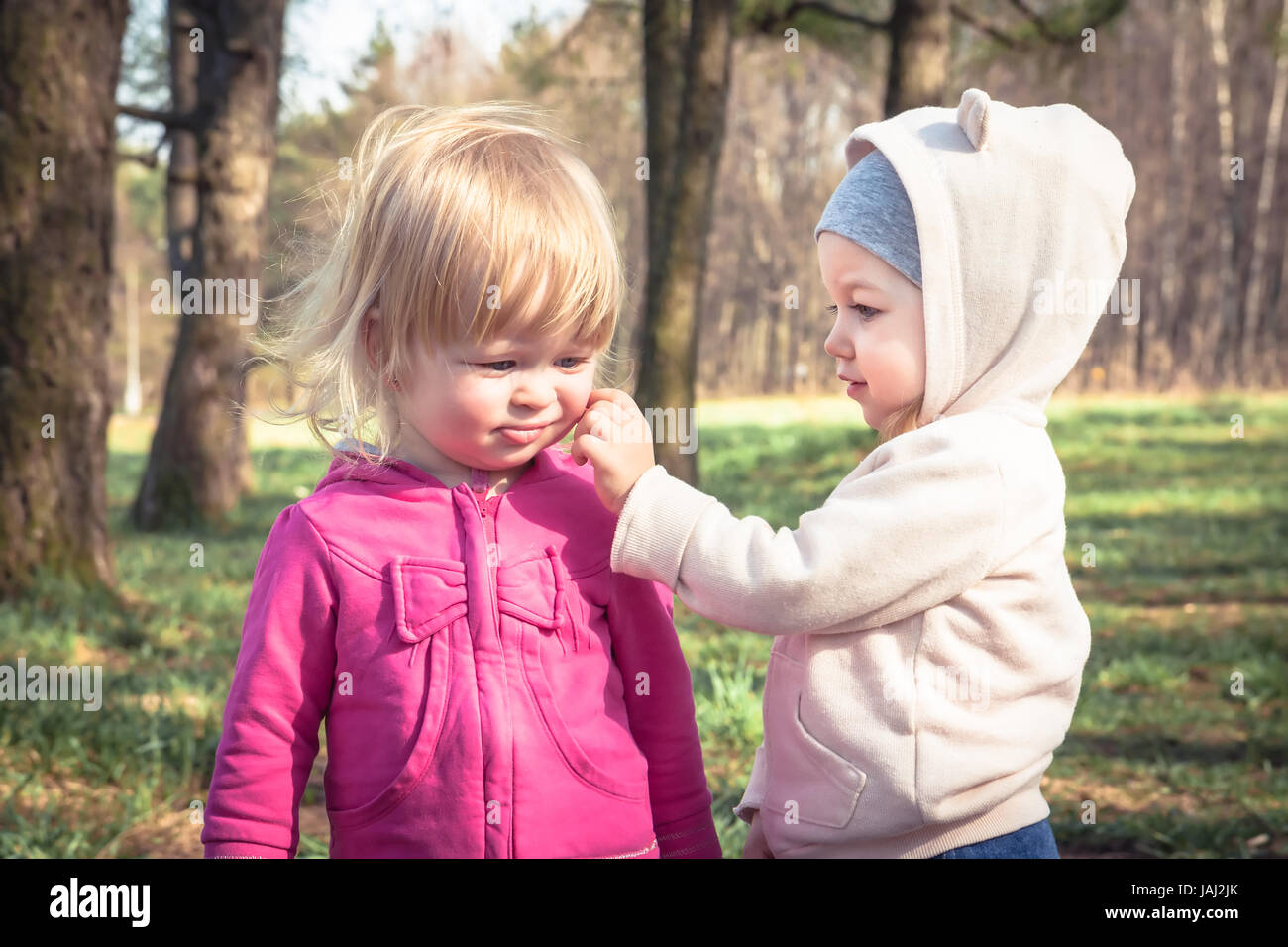 Two cute baby girls playing together in park symbolizing children friendship and childhood Stock Photo