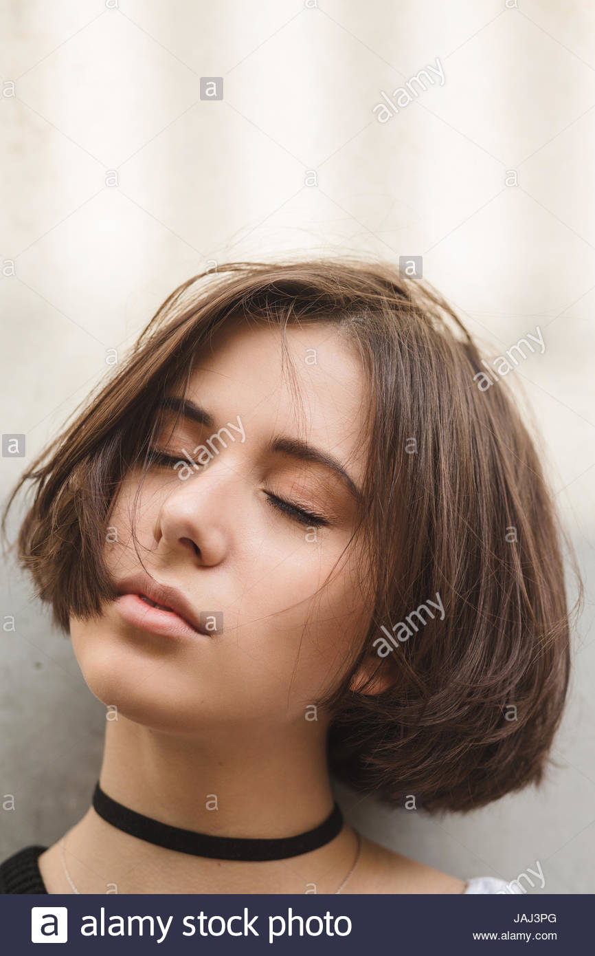 A Stylish Brunette Woman With Short Hair In White Pants And A Top