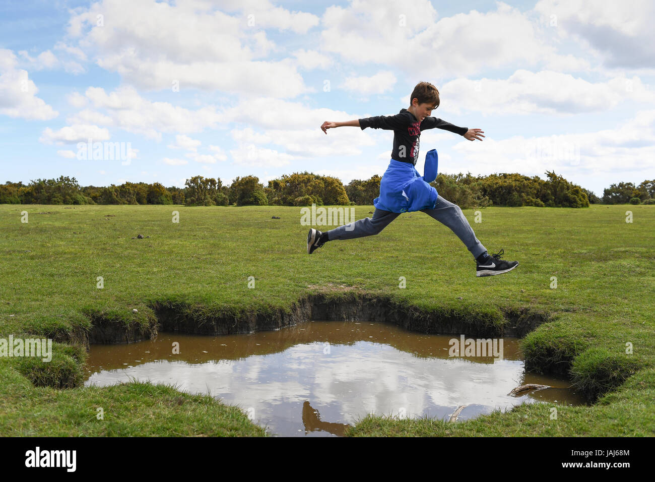 Young boys play jumping over puddles in the New Forest Stock Photo