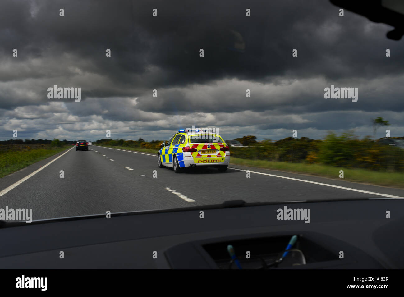 A BMW Police car speeds along a duel carriageway on a call to an emergency with lights ablaze viewed from inside a car Stock Photo