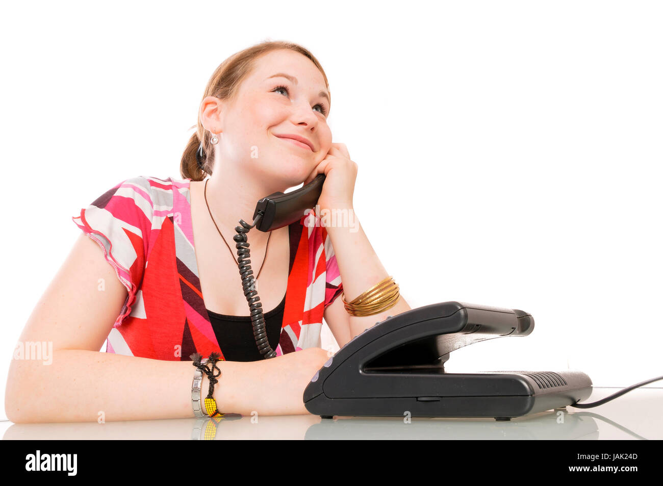 Mädchen, Schülerin telefoniert mit Festnetztelefon vor weißem Hintergrund. Stock Photo