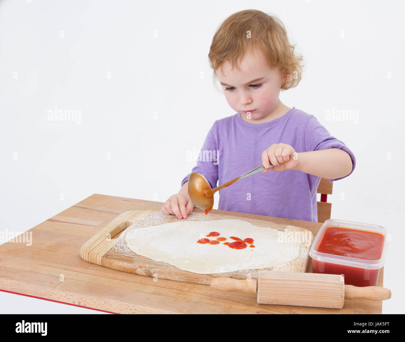 little girl making pizza. studio shot on light grey background Stock Photo