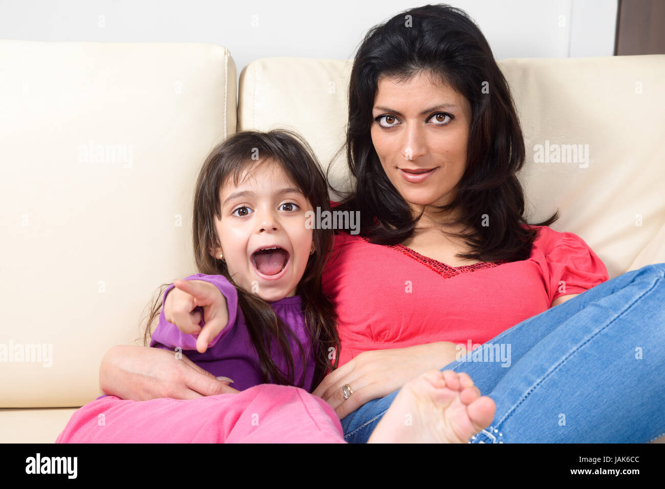 Mother and daughter lying on the couch, watching with amazement straight in front of them Stock Photo
