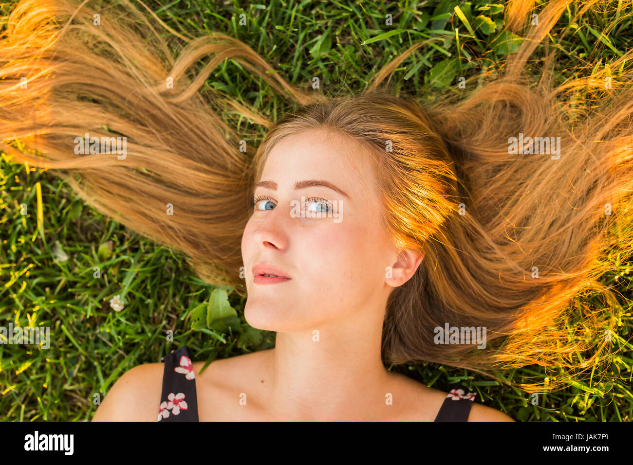 Portrait of a young woman lying on the grass Stock Photo - Alamy