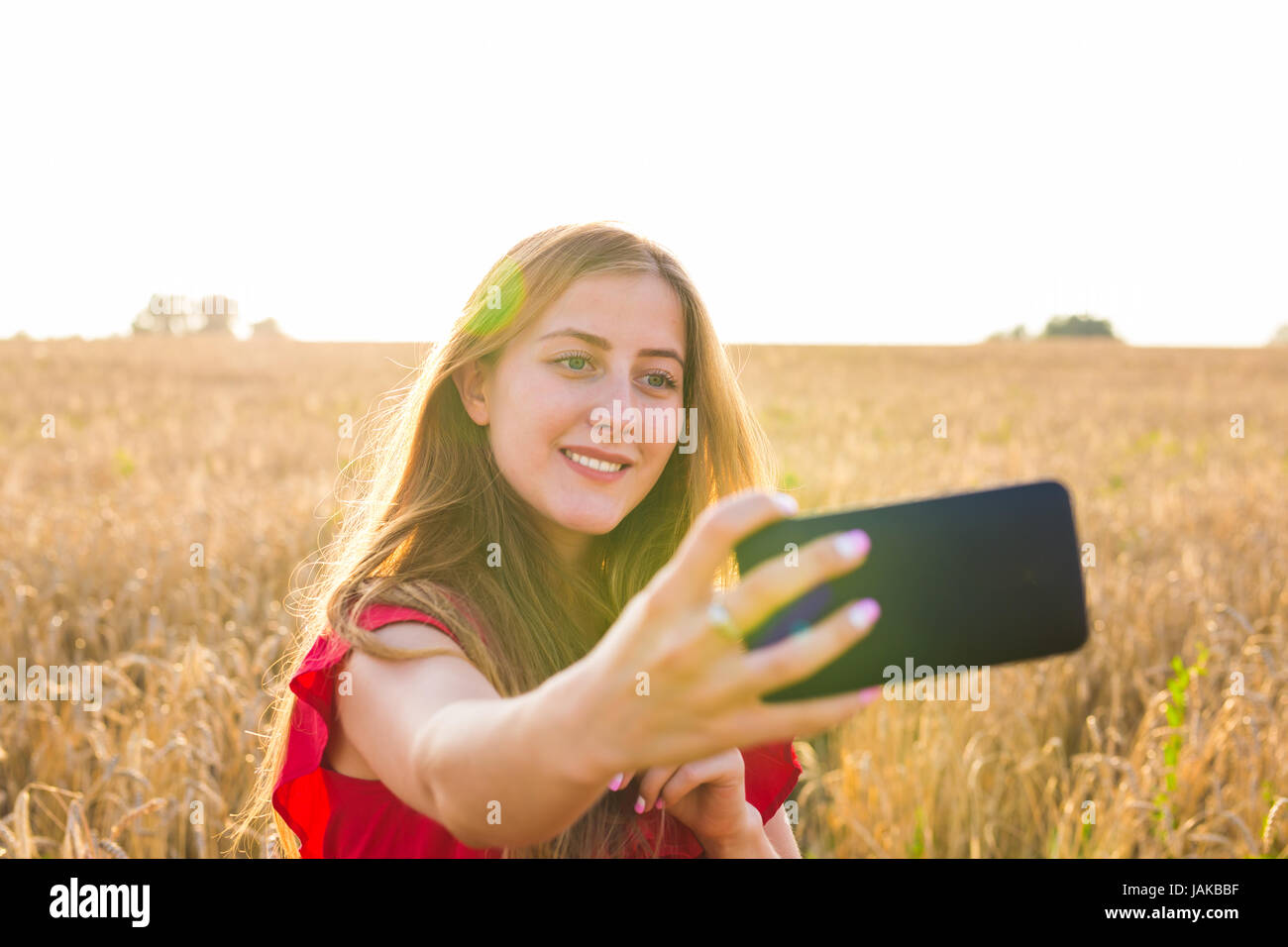 Young happy woman smiling while taking selfie picture with mobile phone ...