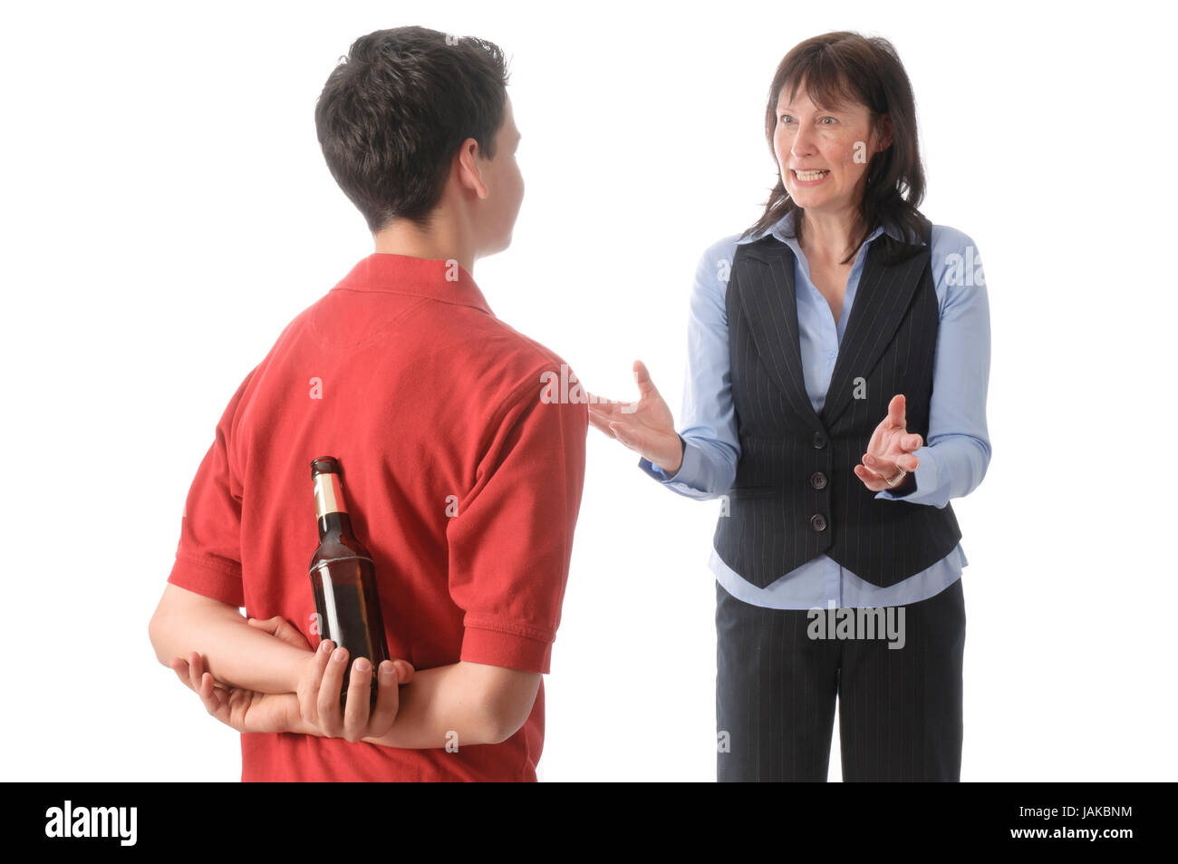 Mutter erwischt ihren jugendlichen Sohn mit einer Flasche Bier und schimpft mit ihm vor weißem Hintergrund. Stock Photo