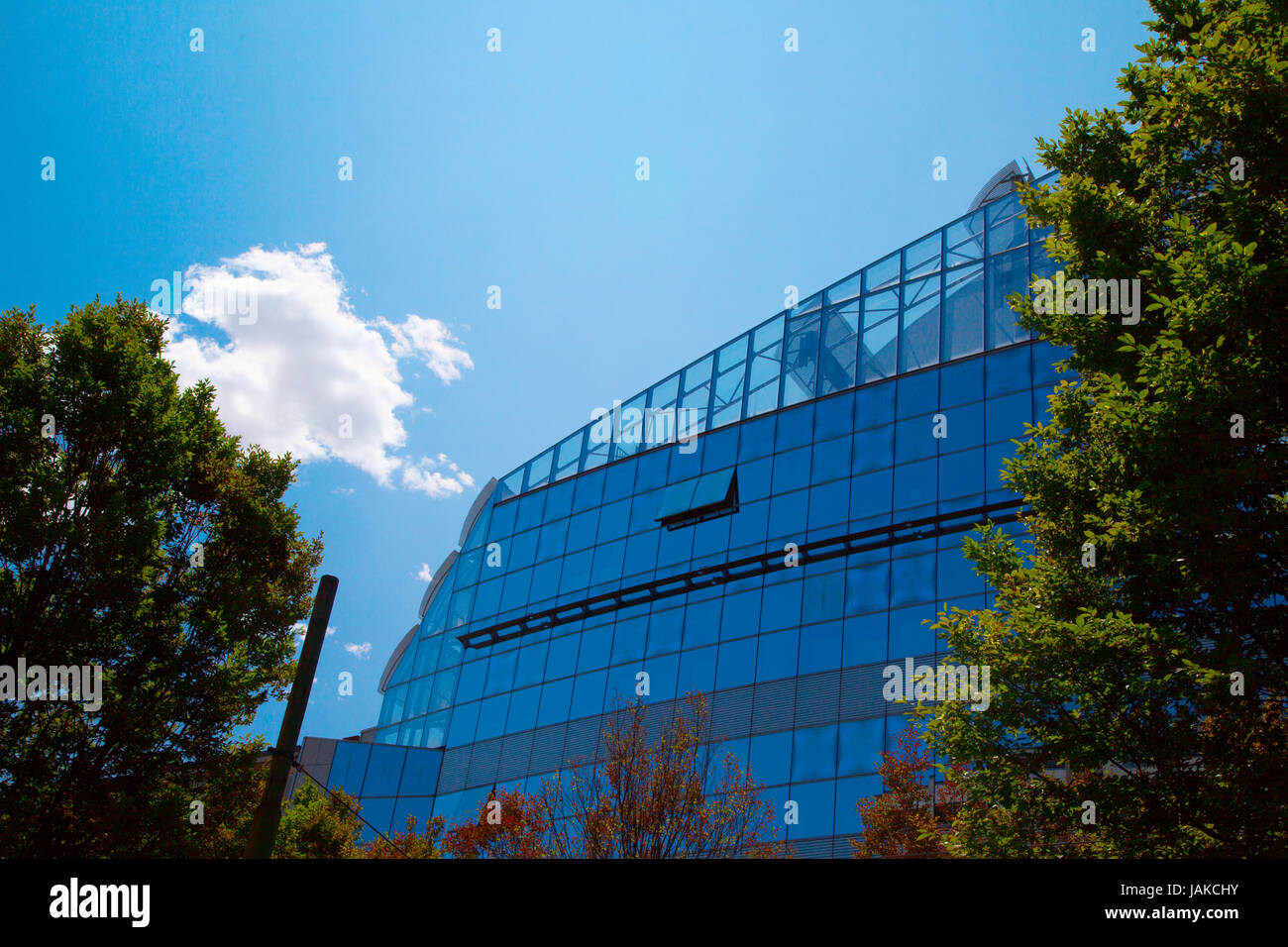 A glass building under a blue sky with a cloud Stock Photo - Alamy