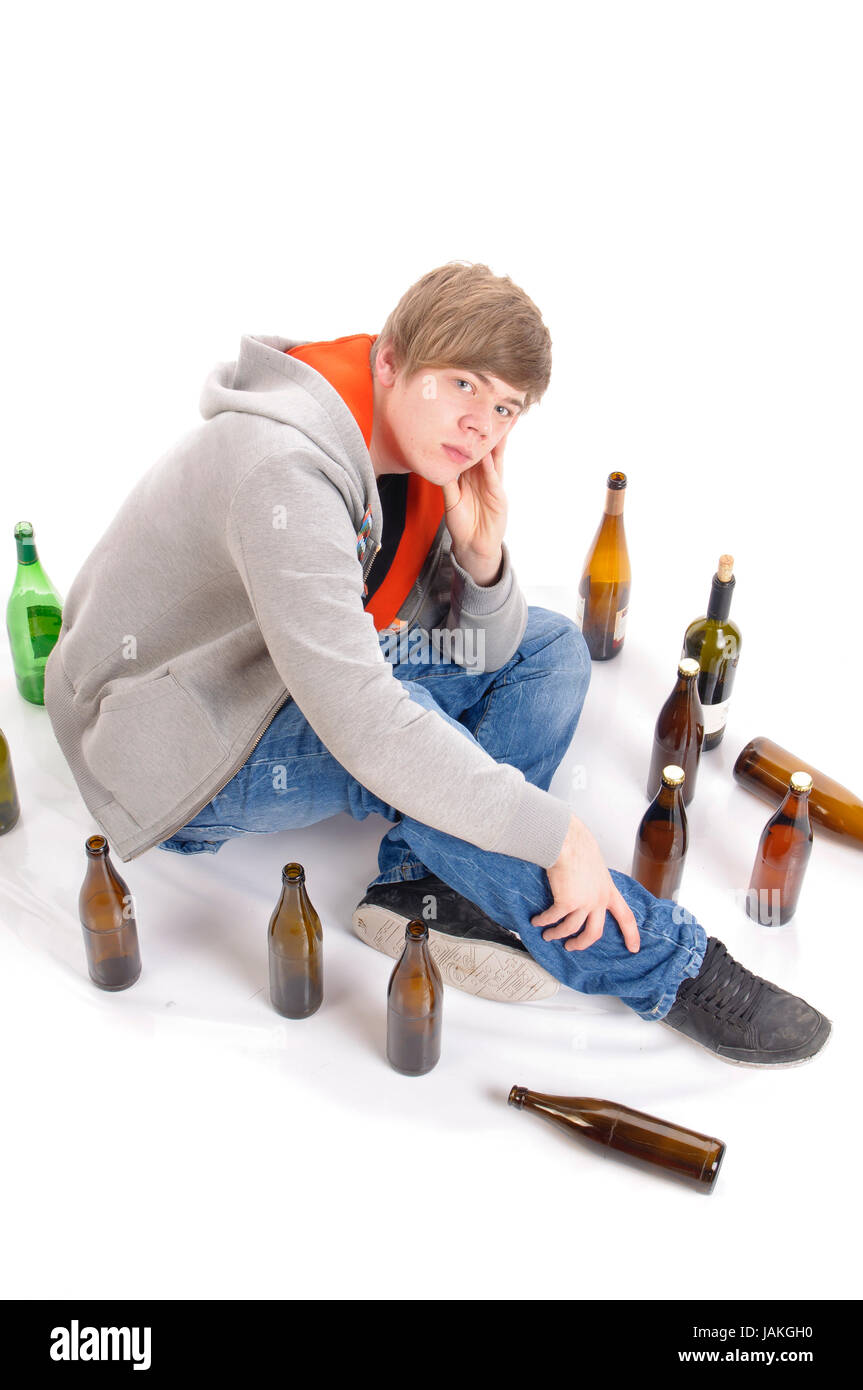 Junger Mann mit kurzen blonden Haaren sitzt auf dem Boden mit Bierflaschen und ist betrunken, isoliert vor weißem Hintergrund Stock Photo