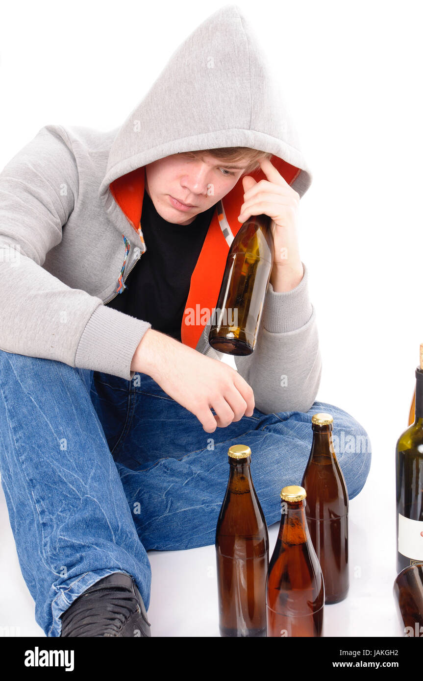 Junger Mann mit kurzen blonden Haaren sitzt auf dem Boden mit Bierflaschen und ist betrunken, isoliert vor weißem Hintergrund Stock Photo