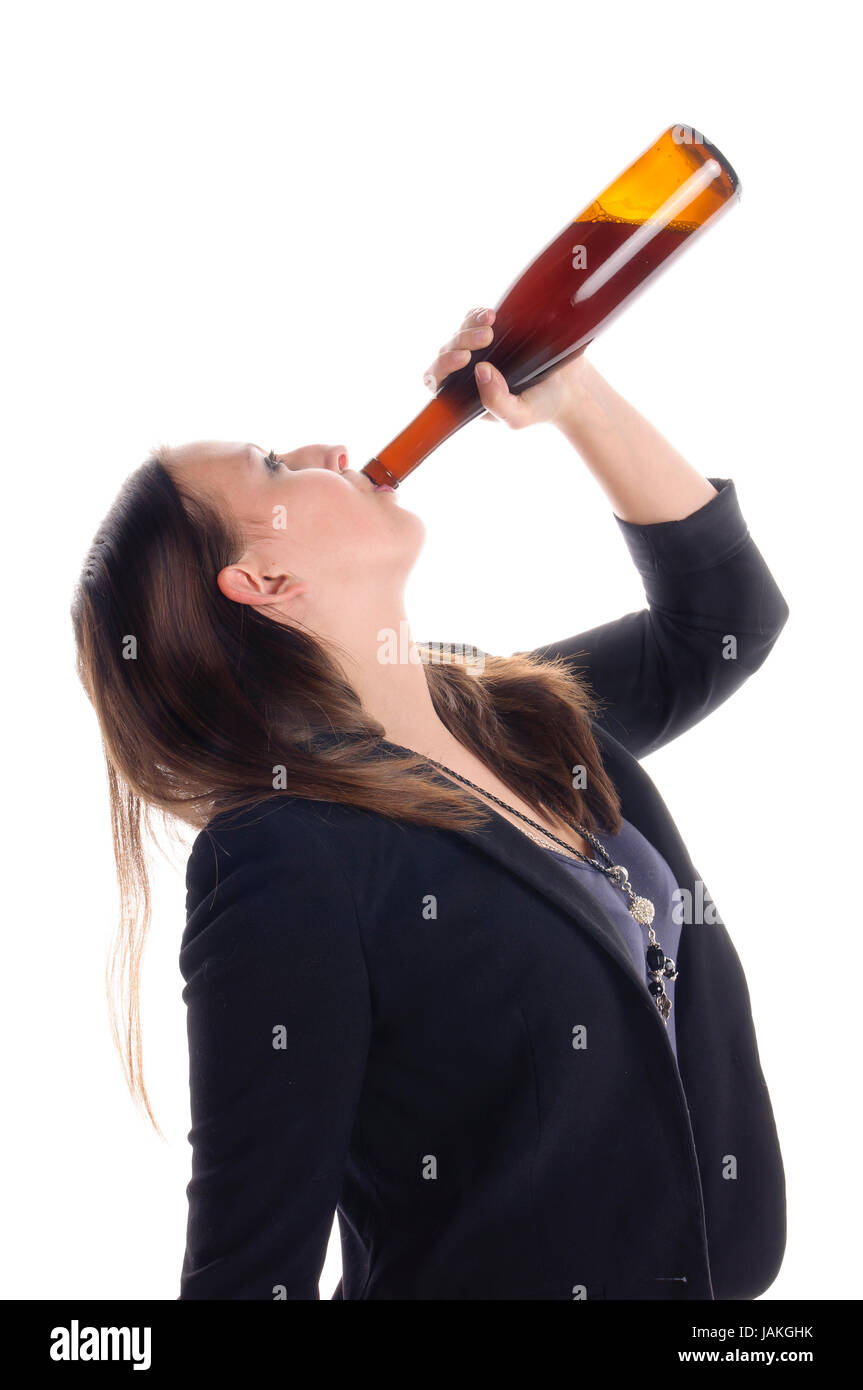 Junge Frau in Rock und Jacket steht vor weißem Hintergrund und trinkt aus einer Flasche Wein. Stock Photo