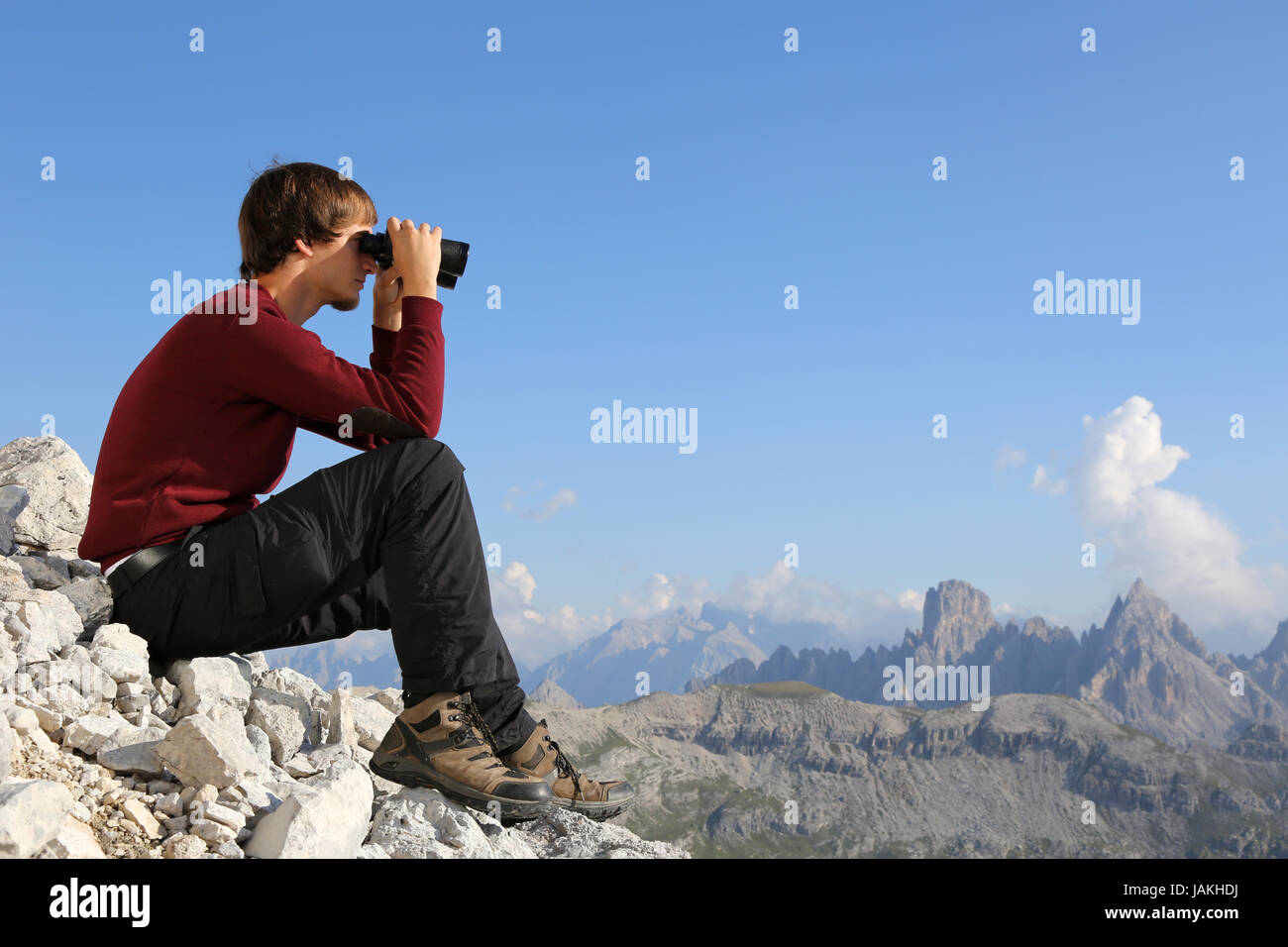 Ein junger Mann schaut in den Bergen durch ein Fernglas Stock Photo