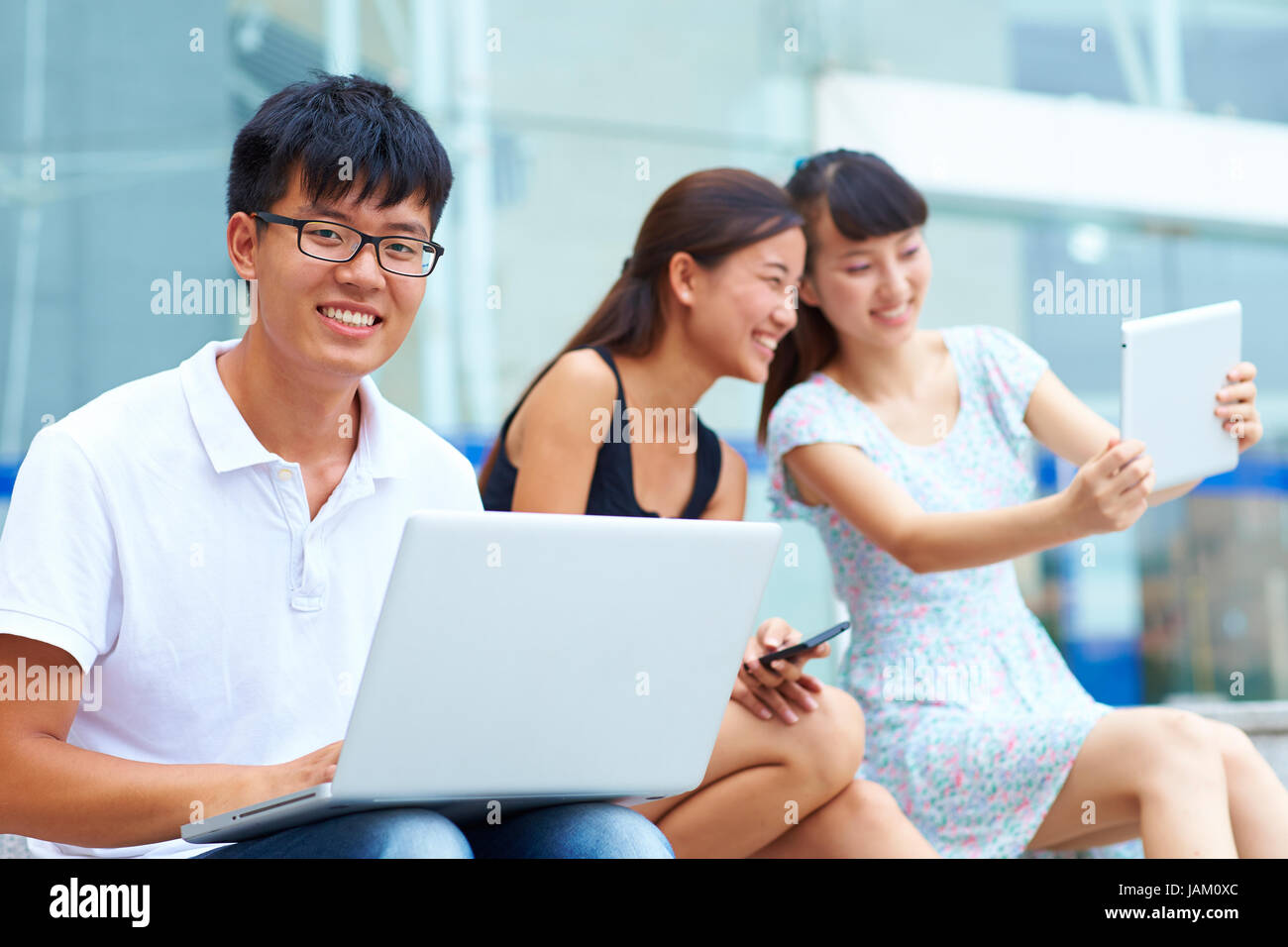 young asian college student using laptop or tablet together outdoor