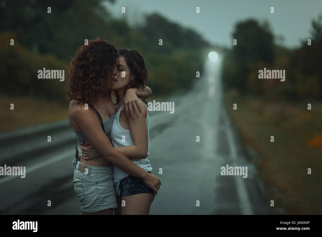 Girls lesbians kissing under the heavy rain. They got wet. Stock Photo