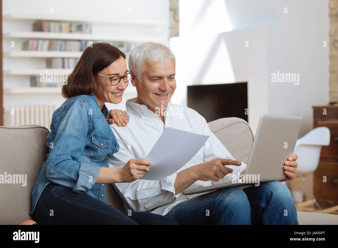 couple using their laptop to pay their bills at home in the living room Stock Photo