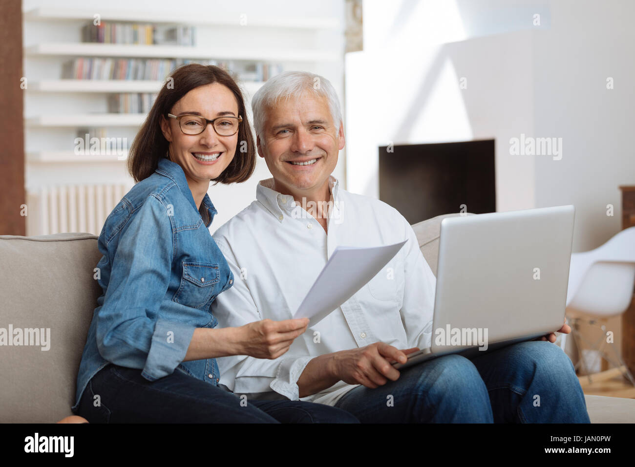 couple using their laptop to pay their bills at home in the living room Stock Photo