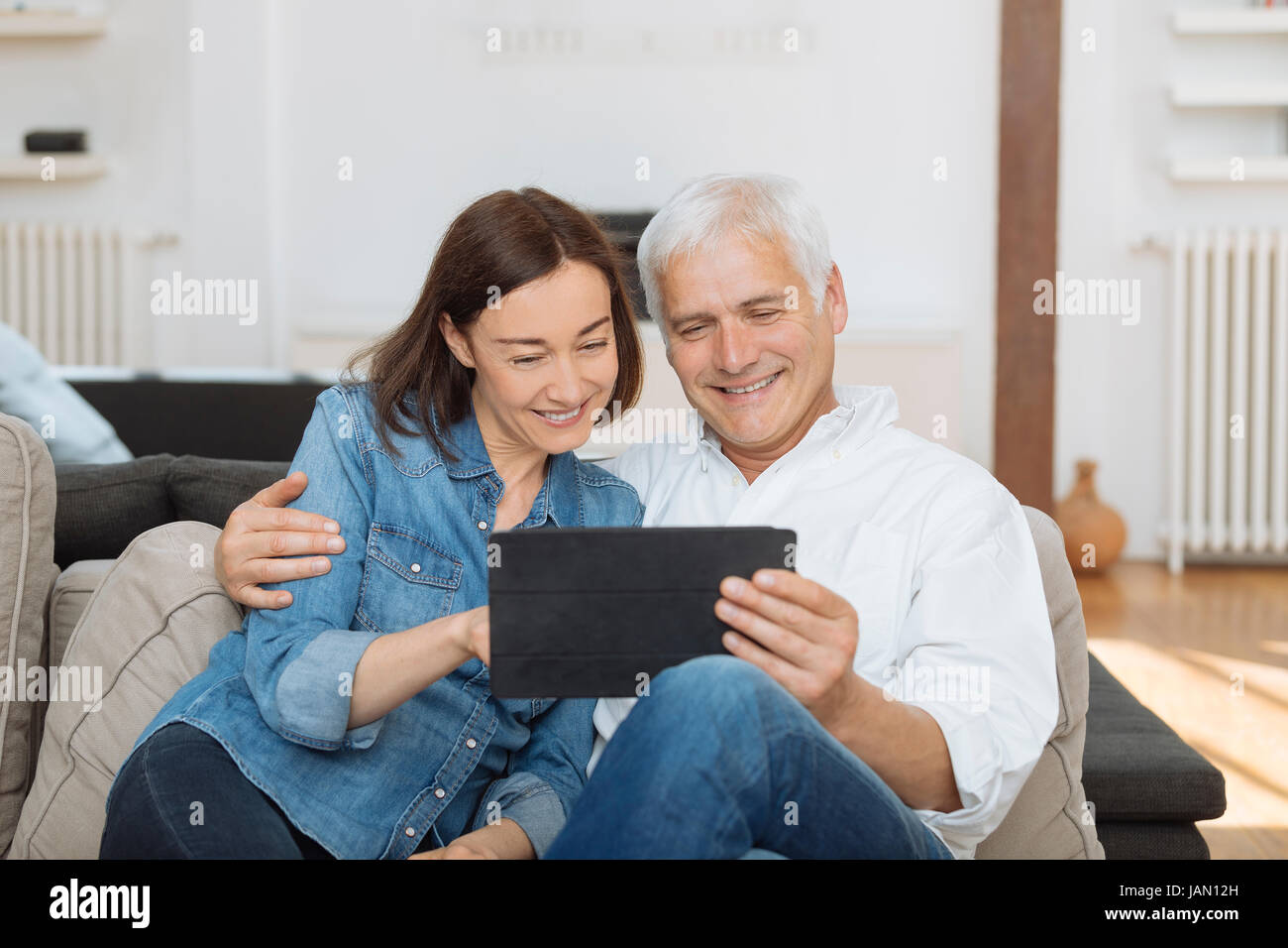 Mature couple at home websurfing with tablet Stock Photo