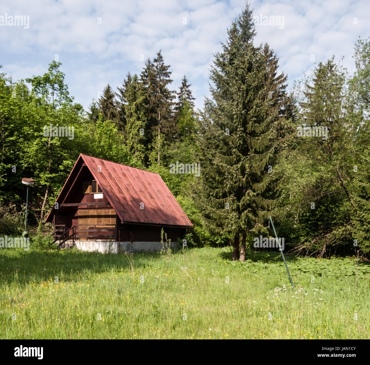 abandoned chalet on meadow with trees around and blue sky with clouds on Dierova settlement near Orava river and Kralovany city in Slovakia Stock Photo