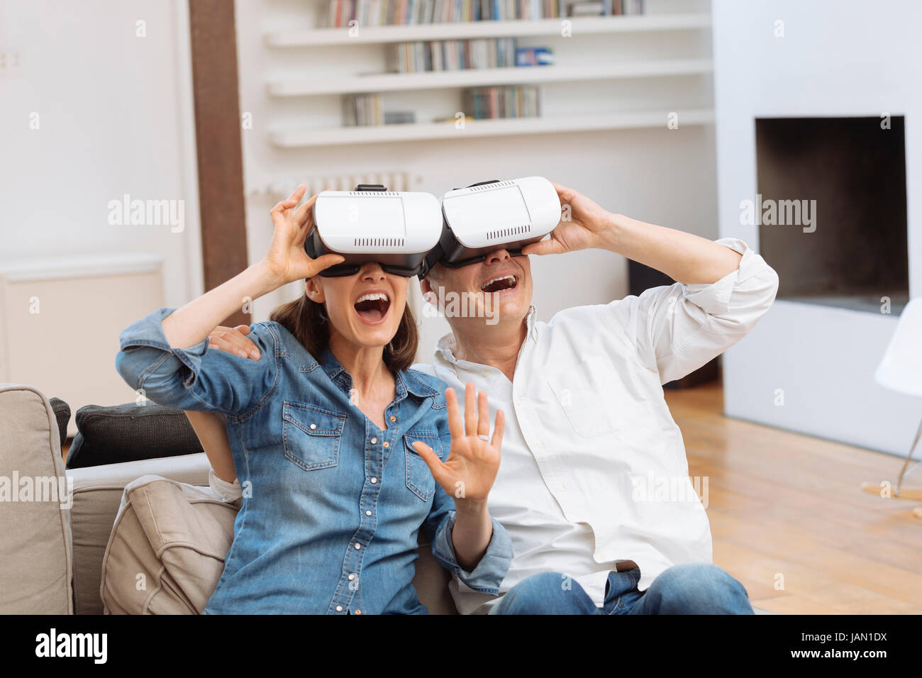 Mature couple using virtual reality headset in living room Stock Photo