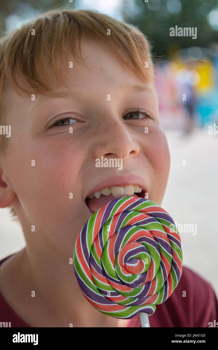 Close up of Eight Years Child Licking Colorful Round Lollipop Stock Photo
