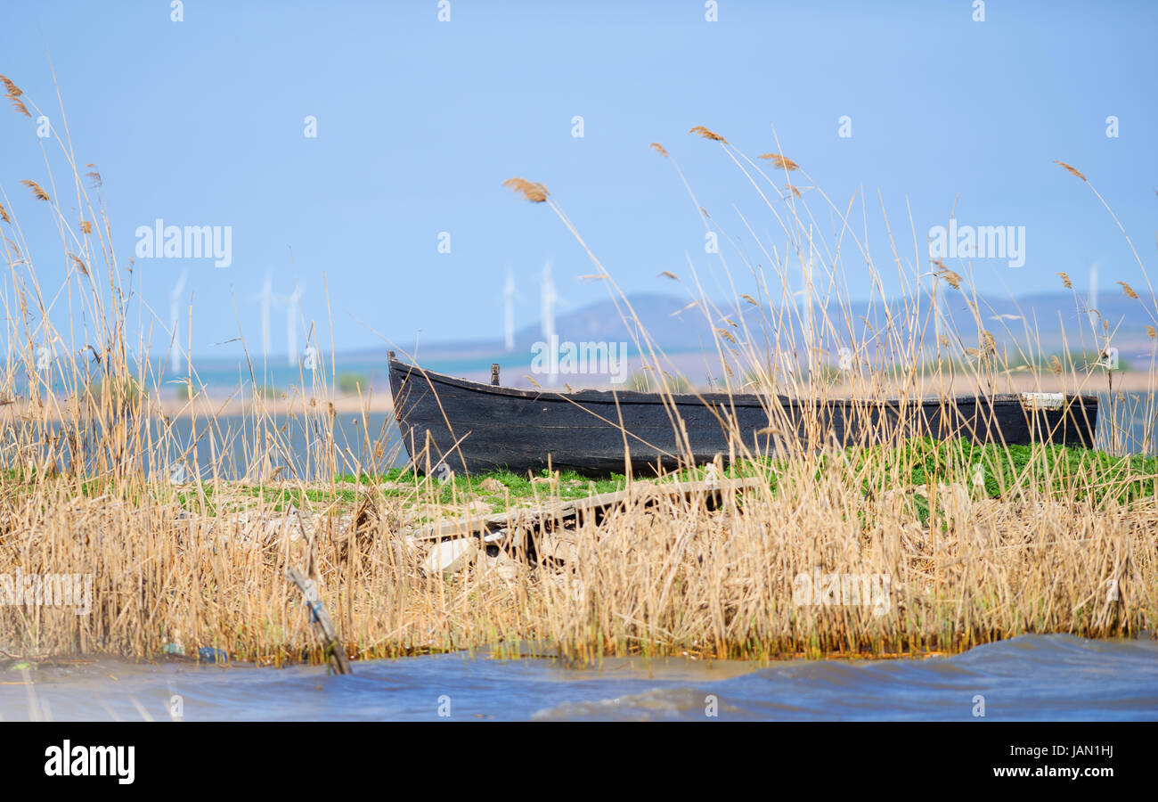 Old boat moored near a rotten wooden bridge on the lake Stock Photo
