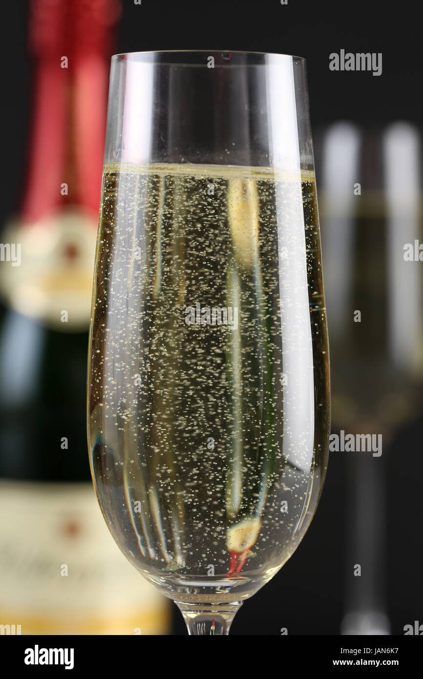 Champagner im Glas mit einer Flasche und weiteren Gläsern im Hintergrund Stock Photo