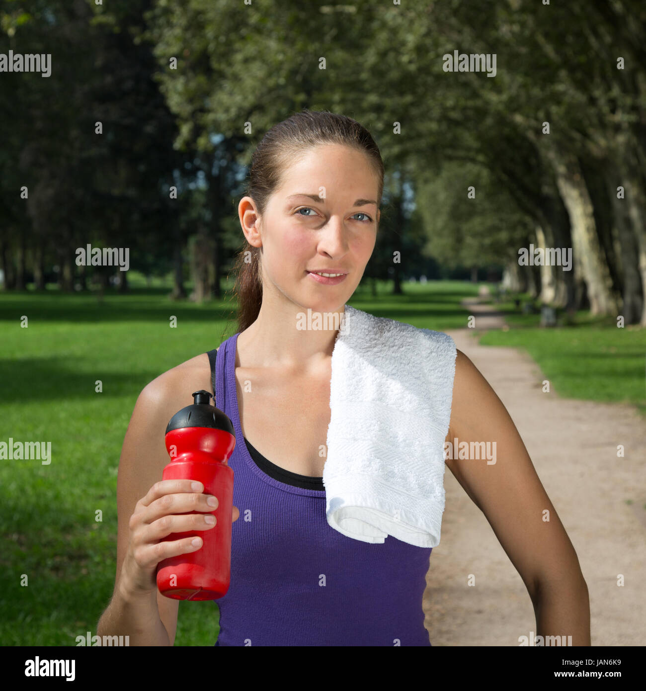 Eine junge Frau mit Getränk macht eine Pause beim Sport oder Laufen Stock Photo