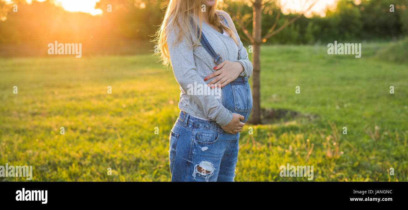 Pregnant woman hugging her belly outdoors Stock Photo - Alamy