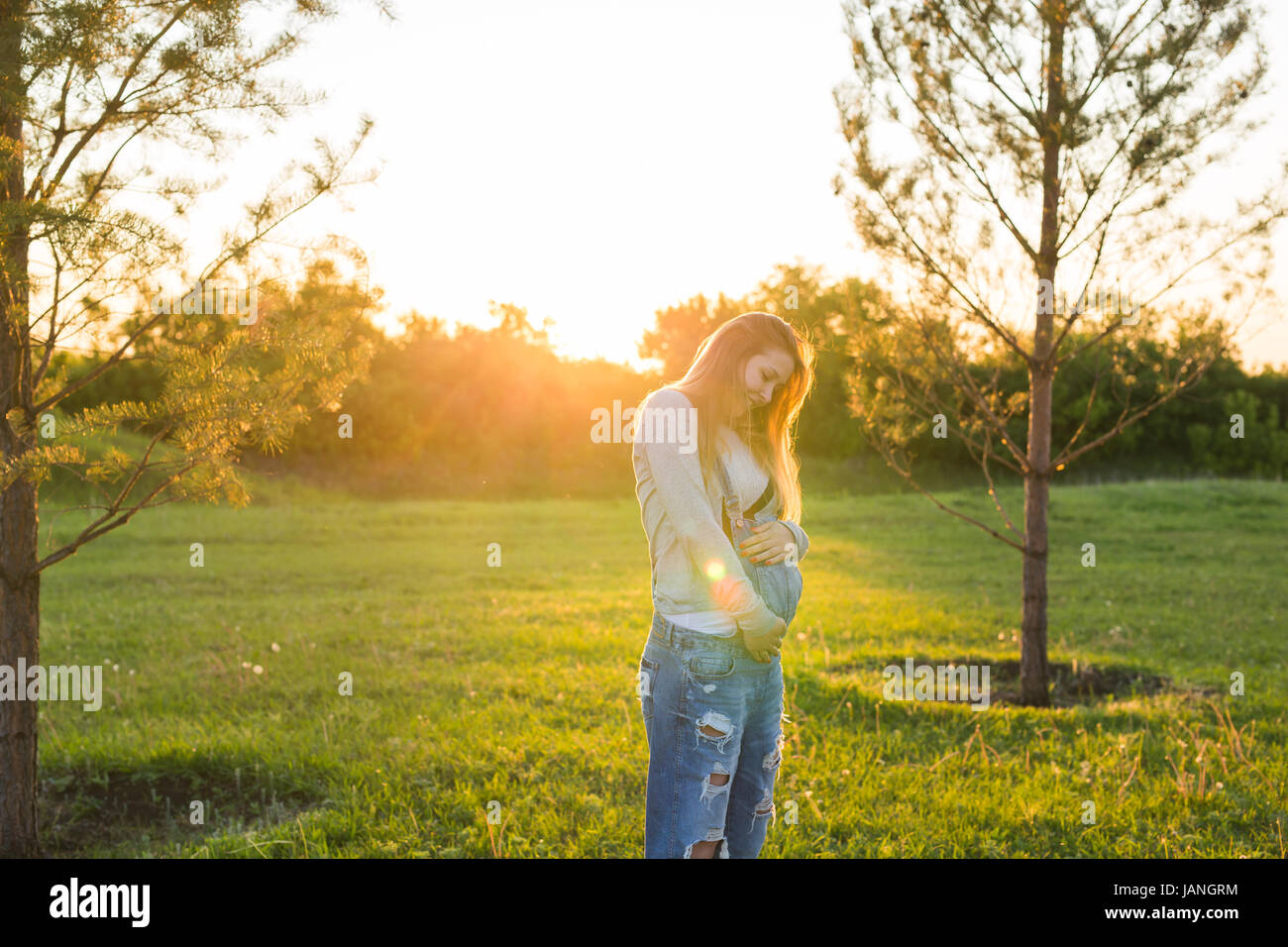 Pregnant woman hugging her belly outdoors Stock Photo - Alamy