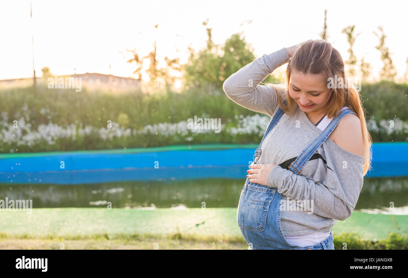 Pregnant woman hugging her belly outdoors Stock Photo - Alamy