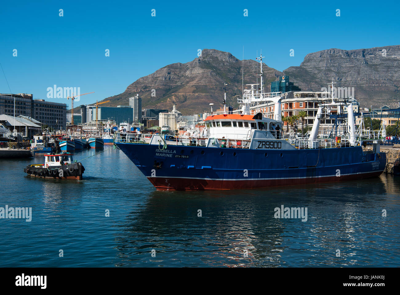 Tug boat pulling a ship out of Cape Town harbour with Table Mountain in the background Stock Photo