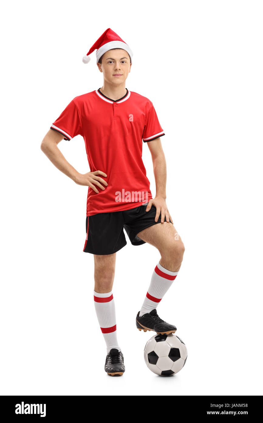 Full length portrait of a teenage soccer player wearing a Christmas hat and pressing a football isolated on white background Stock Photo