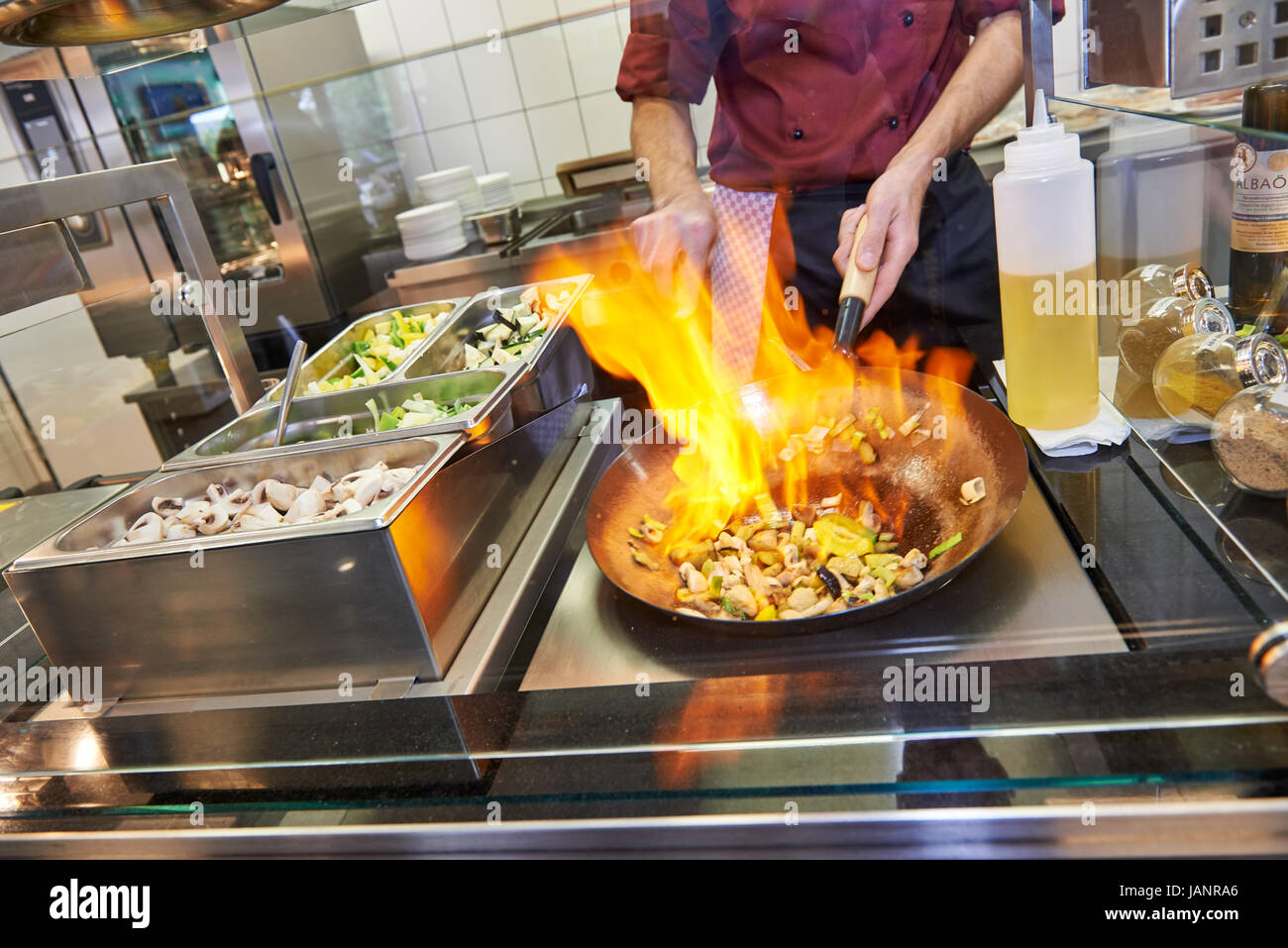 cook in a commercial kitchen is flambeing in a frying pan Stock Photo