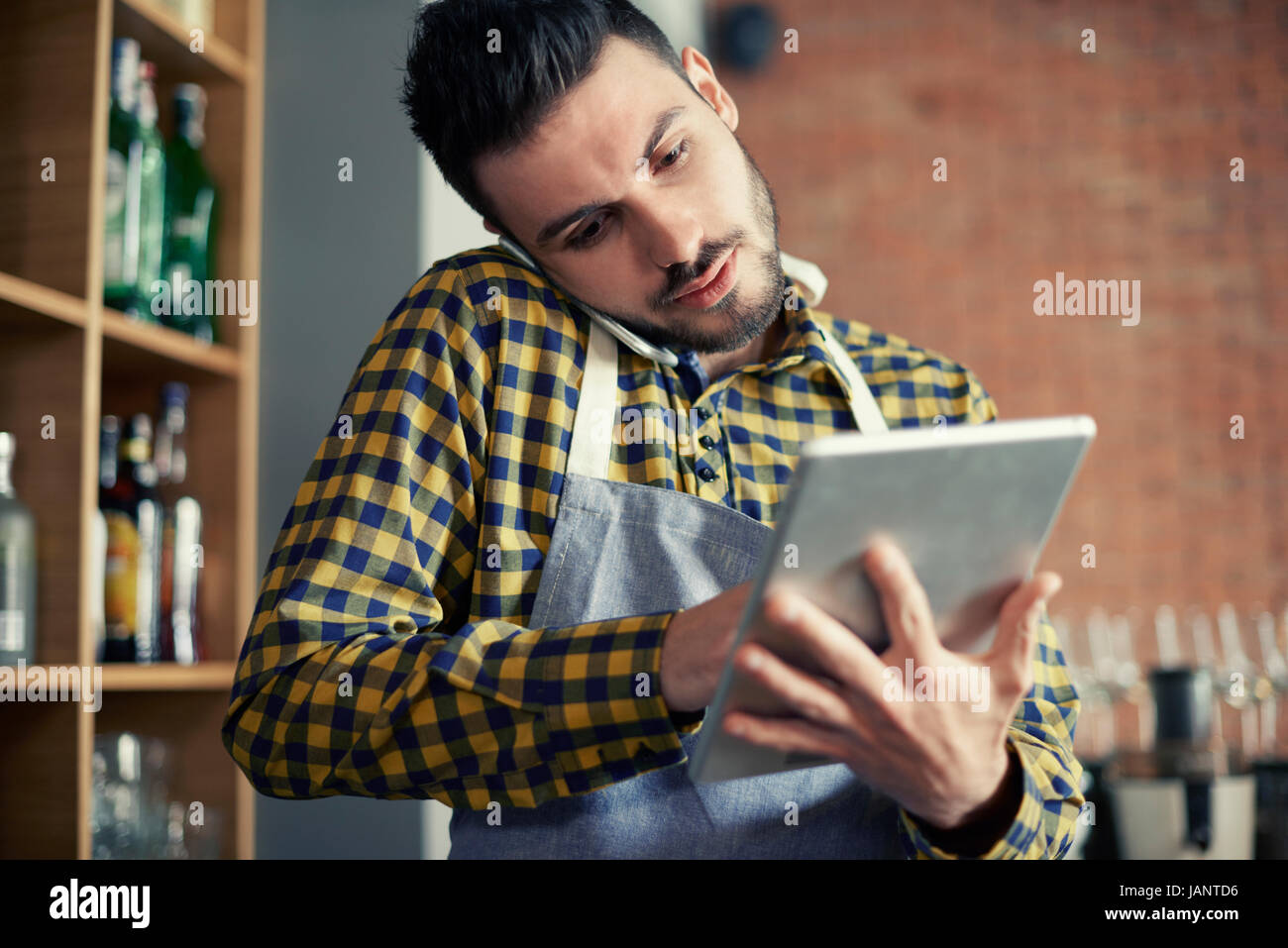 Waiter using smart phone and digital tablet Stock Photo