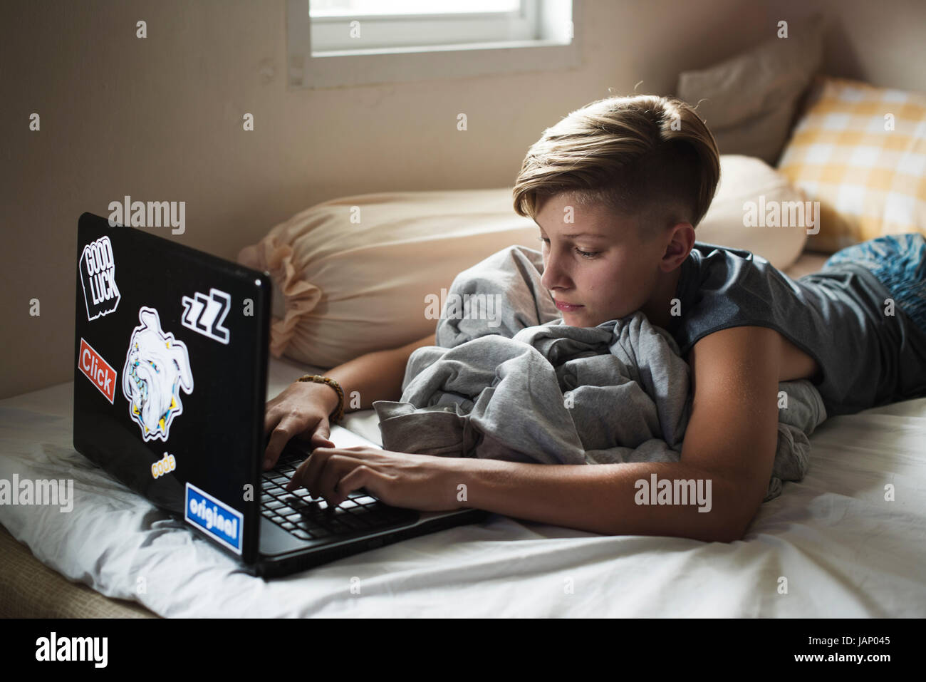Young caucasian boy lying using computer laptop on bed Stock Photo - Alamy