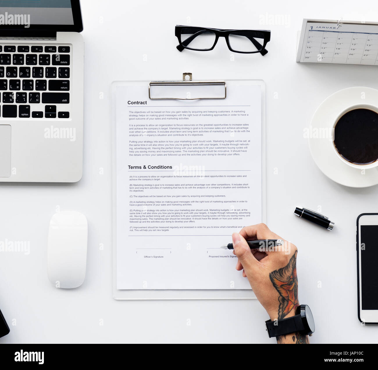 Aerial view of tattoos hand signing paper workspace Stock Photo - Alamy