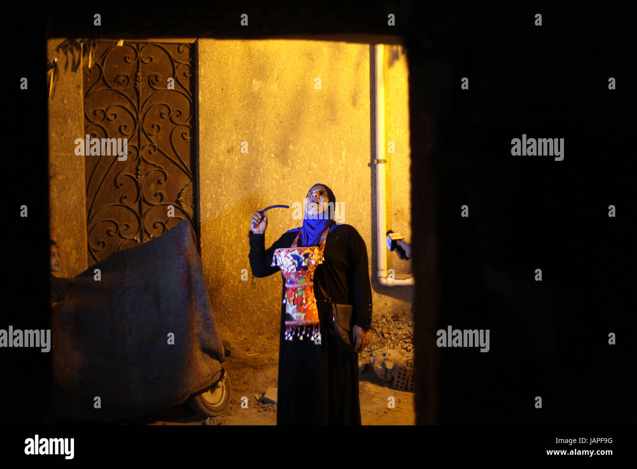 (170607) -- CAIRO, June 7, 2017 (Xinhua) -- Dalal Abdul Qader sings traditional religious song to awaken people for the pre-dawn suhoor meal before starting their daylong fast in Maadi district of Cairo, Egypt, on June 6, 2017. This tradition dates back to the Fatimid Caliphate nine centuries ago, when the Musaharati, or Ramadan drummer, was the only means to awaken people for sohoor since there were no alarm clocks or loudspeakers in mosques at that time. For Abdul Qader, the job of Musaharati is not only a way to earn a living, but it is also a revival of an old tradition that brings up love Stock Photo