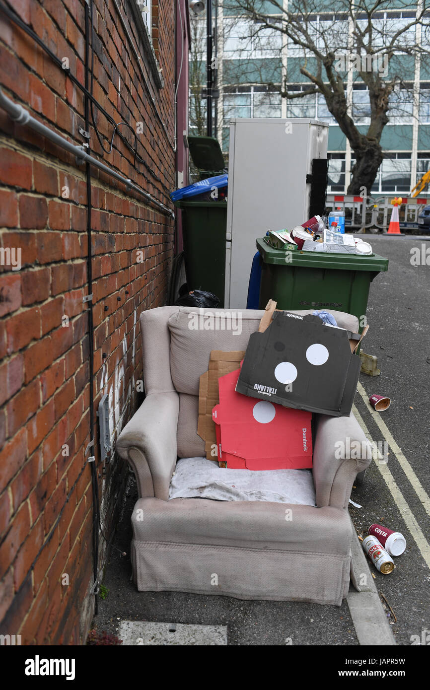 Rubbish overflowing and dumped at roadside, including a fridge freezer and chair. Stock Photo