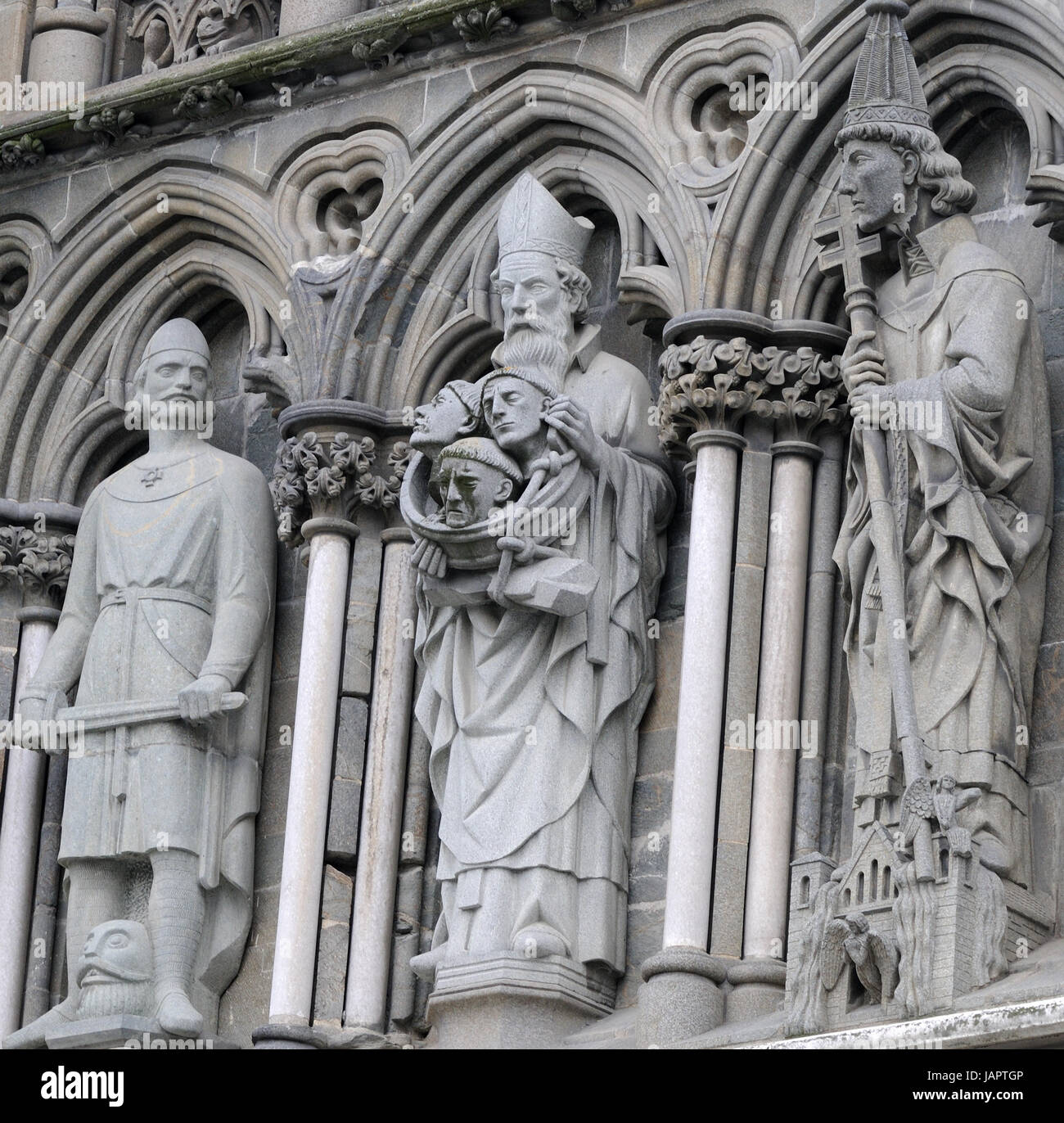 Detail of the West Front of Nidaros Cathedral:  a statue of  Bishop Sigurd  holding the heads of his three nephews in a bowl. To his left is Olaf Tryg Stock Photo