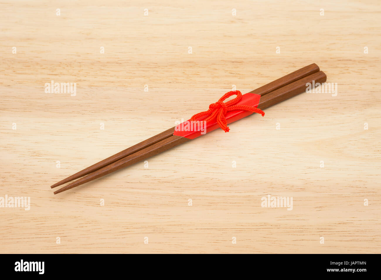 Japanese wooden chopsticks wrapped in red paper and red rope on white background. Stock Photo
