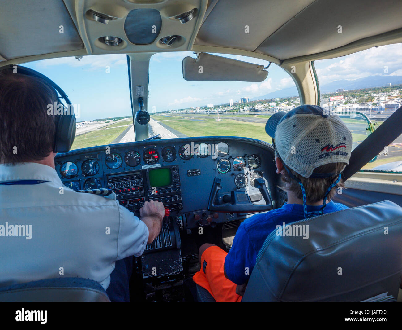 young boy in baseball cap in the co-pilot seat of a small airplane approaching the runway on the british virgin island of tortola Stock Photo