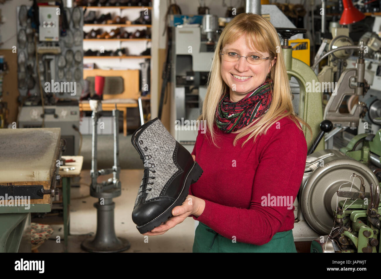 Shoemaker, woman holding finished shoe in hands, at back workshop, Kainisch, Styria, Austria Stock Photo