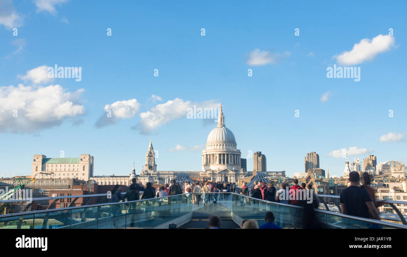 View of the Millennium bridge in London with St Paul cathedral and tourists and commuters walking Stock Photo