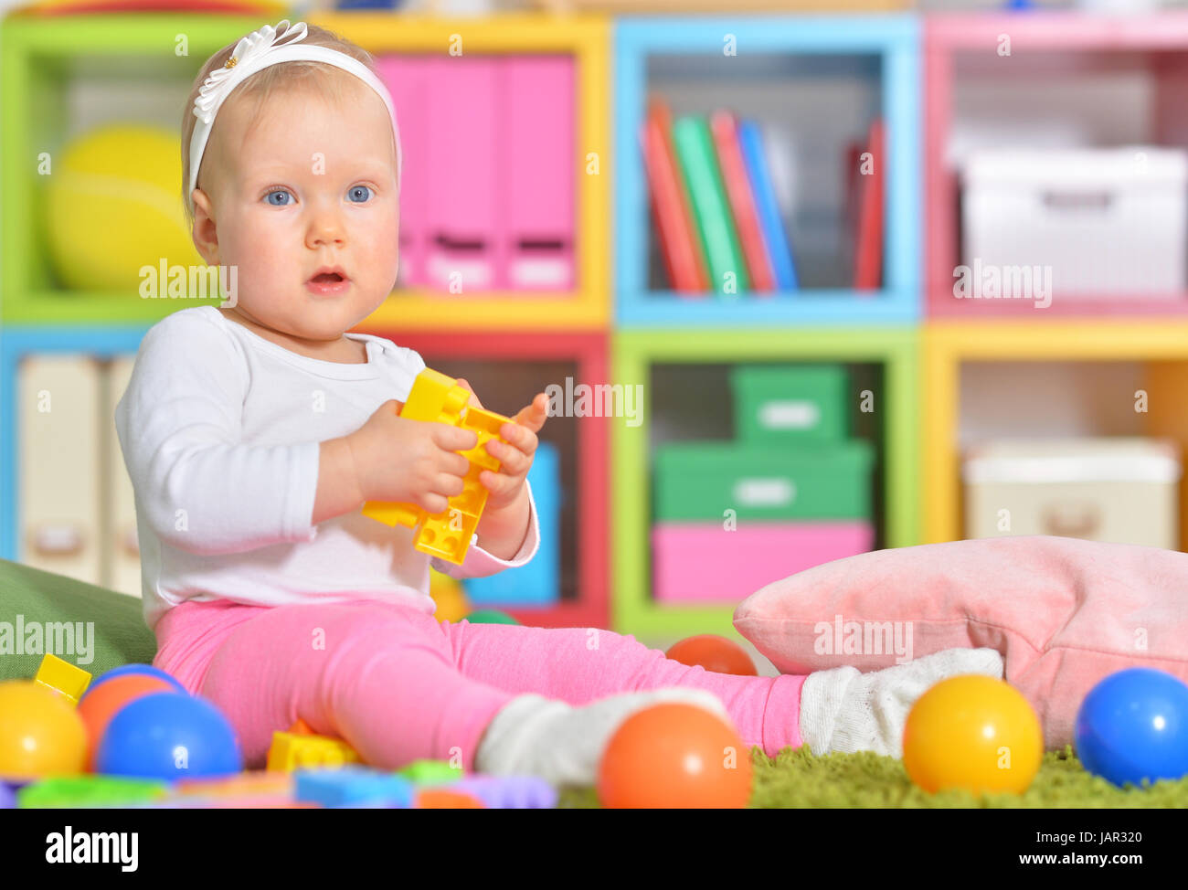 Adorable little child playing with colorful toys in childrens room ...