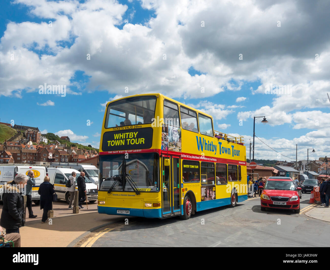 A bright yellow open topped double decker bus which takes tourists on a tour around the seaside town of Whitby Stock Photo